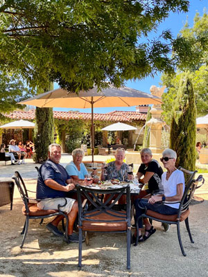 5 people sitting at a patio table for a wine tasting